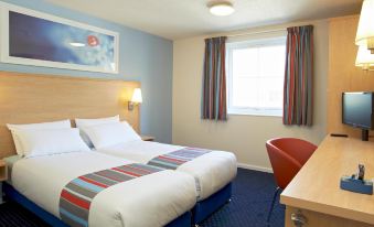 a modern hotel room with two beds , a window , and a desk , all neatly arranged at Travelodge Oswestry