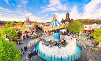 a bustling amusement park with various rides and attractions , including a carousel and a water fountain at Hotel am Rhein