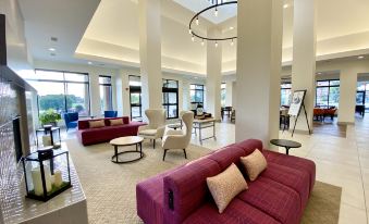 a large , modern living room with multiple couches and chairs arranged in various positions , creating a comfortable and inviting atmosphere at Hilton Garden Inn Oconomowoc