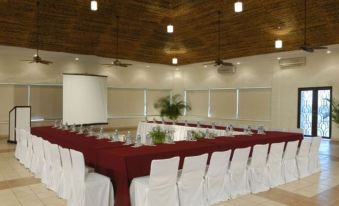a conference room with a red table and white chairs is set up for an event at El Cid Marina Beach Hotel