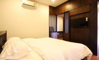 a modern bedroom with a white bed , wooden walls , and an air conditioner on the wall at Rongsang Resort