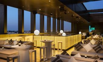 a modern bar with white stools and chairs , a yellow counter , and a view of the city at Hotel Sa Barrera - Adults Only