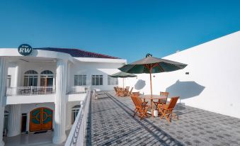 a rooftop patio with a dining table and chairs , an umbrella , and a view of the ocean at Griya RW Family Guest House Redpartner