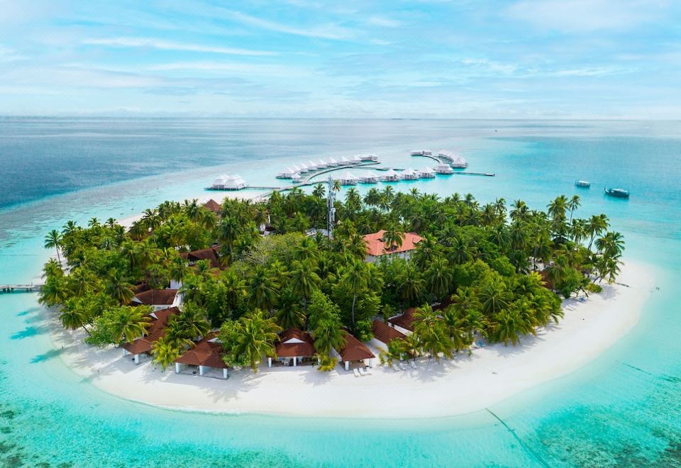 aerial view of a tropical island with a resort on it , surrounded by clear blue water and lush green vegetation at Diamonds Athuruga Maldives Resort & SPA
