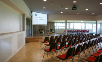 an empty conference room with rows of chairs arranged in front of a projector screen at Dialoghotel Eckstein