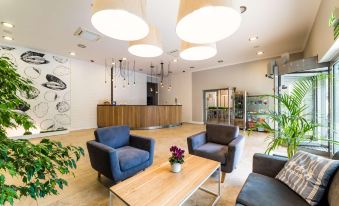 a modern and spacious lobby with a reception desk , two couches , and multiple pendant lights at Best Western Hotel Jurata