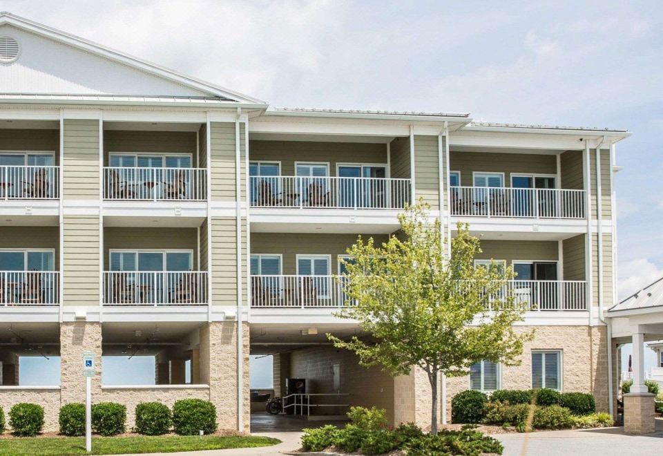 a multi - story building with multiple balconies and windows , surrounded by trees and a parking lot at Island Inn & Suites, Ascend Hotel Collection
