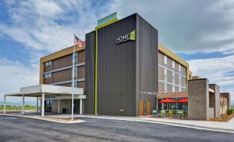 "a large , modern building with a green and white sign that says "" home "" on it" at Home2 Suites by Hilton Helena