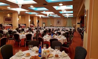 a large banquet hall filled with tables and chairs , ready for a formal event or a wedding reception at Hotel Philippos