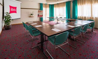 a conference room with multiple chairs arranged in a semicircle around a table , and a projector on the wall at Ibis Firenze Nord Aeroporto