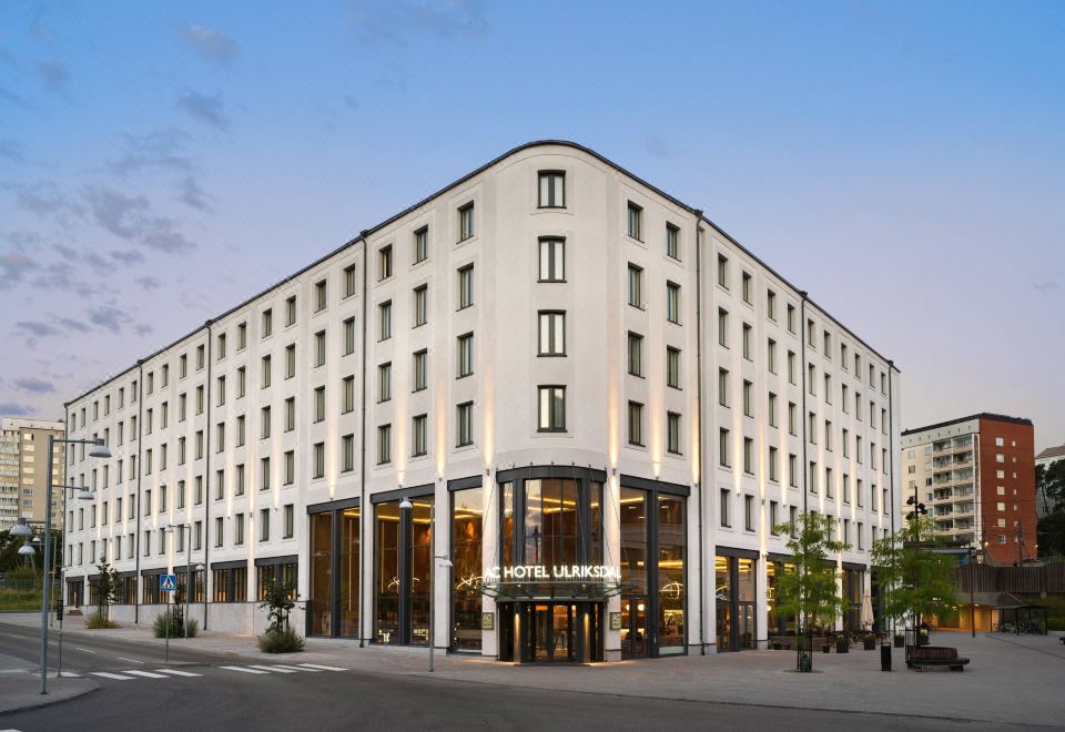 a large white hotel building in the middle of a city street , surrounded by other buildings at AC Hotel Stockholm Ulriksdal