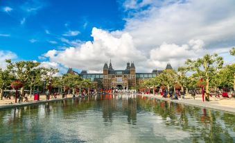 a large , ornate building with a reflecting pool in front of it , surrounded by trees and people at Nova Hotel