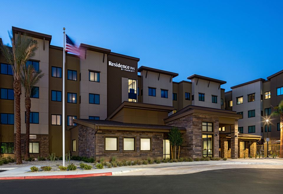a large hotel with a stone facade and american flag in front of it , set against a blue sky at Residence Inn Riverside Moreno Valley