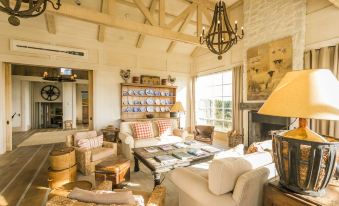 a cozy living room with a wooden ceiling , white walls , and a fireplace , filled with furniture such as couches and chairs at Rosewood Cape Kidnappers