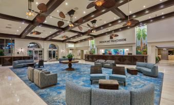 a large hotel lobby with a reception desk , seating areas , and a bar area in the center at Newport Beachside Hotel & Resort