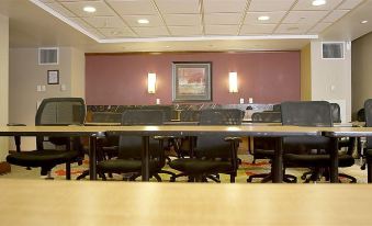 a conference room with multiple tables , chairs , and a tv mounted on the wall , surrounded by artwork at Hotel Executive Suites