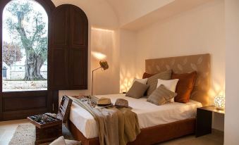 a cozy bedroom with a large bed , a lamp on the nightstand , and a window at Ottolire Resort