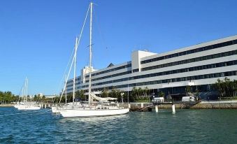 a sailboat is docked in front of a large white building with palm trees in the background at Marina Park