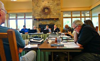 a group of people sitting around a table in a conference room , engaged in conversation at Nature Inn at Bald Eagle