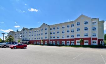 a parking lot with a red car and a building with multiple floors , under a clear blue sky at Homewood Suites by Hilton Dover