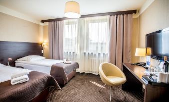 a hotel room with two beds , a desk , and a chair , along with curtains and a lamp at Hotel Diament Zabrze - Gliwice