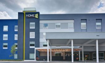 a modern hotel with a blue and white facade , large windows , and a covered parking area at Home2 Suites by Hilton Fort Mill