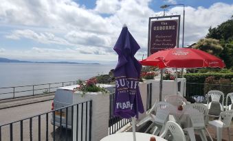 a restaurant with umbrellas and tables , overlooking a body of water , possibly a lake or the ocean at The Osborne