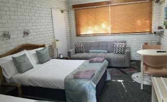 a hotel room with two beds , a couch , and a coffee table , all arranged neatly in the space at Holland Park Motel