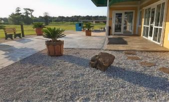 a gravel courtyard with a small tree in a pot and a rock near the entrance at Amelia Extended Stay & Hotel