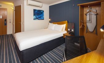 a hotel room with a king - sized bed , a desk , and a television mounted on the wall at Holiday Inn Express Northampton - South