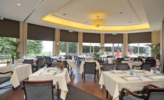 a large , elegant dining room with multiple tables and chairs arranged for a formal event at Fletcher Parkhotel Val Monte