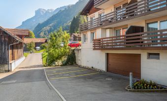 a parking lot with cars parked in front of a house , surrounded by mountains in the background at Annex