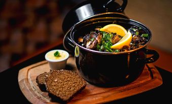 a pot of stew with a slice of lemon and a side of bread on a wooden cutting board at Shannon Springs Hotel