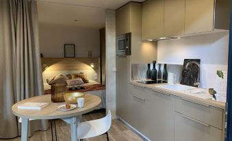 a modern kitchen with white cabinets , a dining table with chairs , and a wine bottle on a tray at Green Resort
