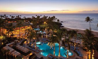 a beautiful resort with a pool surrounded by palm trees and the ocean in the background at Four Seasons Resort Maui at Wailea