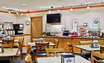 a breakfast nook with a dining table , chairs , and a tv mounted on the wall at Country Inn & Suites by Radisson, Burlington (Elon), NC