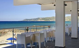 a beautiful outdoor dining area with white chairs and tables , overlooking a beautiful ocean view at Hotel la Playa