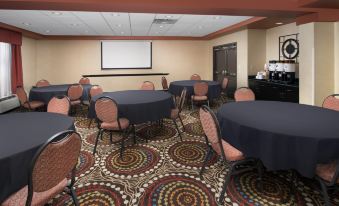 a conference room with tables and chairs , a projector screen , and a carpet with circular patterns at Hampton Inn Lenoir City