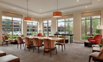 a large , well - lit dining room with multiple tables and chairs arranged for a group of people at Hilton Garden Inn Stony Brook