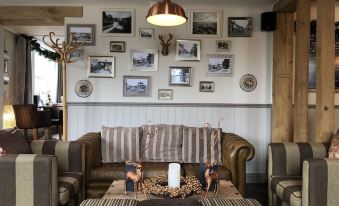 a cozy living room with a brown couch , a coffee table , and various decorative items on the wall at The Ship Inn