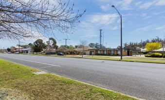 a sunny day with clear skies , clear weather , and clear trees , as well as a road with trees and buildings in the background at Maffra Motor Inn