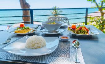 a table is set with various dishes , including a white plate of food and a bowl of salad at Play Phala Beach Rayong