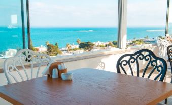 a wooden dining table with two chairs , situated in front of a large window overlooking the ocean at Port Marina Hotel