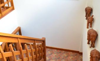 a wooden staircase with red and white striped carpet , leading to a doorway decorated with a mural on the wall at The Indigo House Phrae