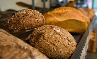 a bakery display case filled with various types of bread , such as loaves and rolls at Hotel Heimatlodge