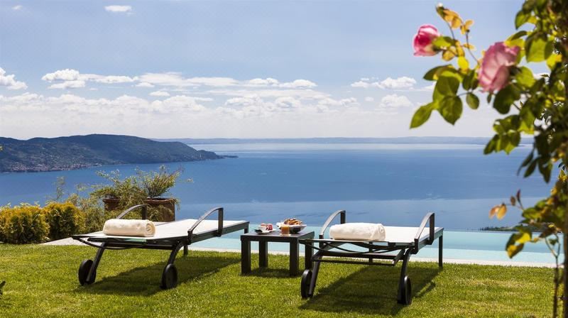 a serene outdoor setting with two sun loungers , a table , and flowers overlooking the ocean at Lefay Resort & Spa Lago di Garda