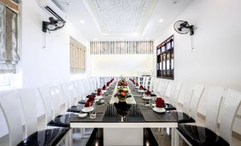 a long dining table set with white chairs , black and white tablecloths , and red napkins at Sepon Boutique Resort