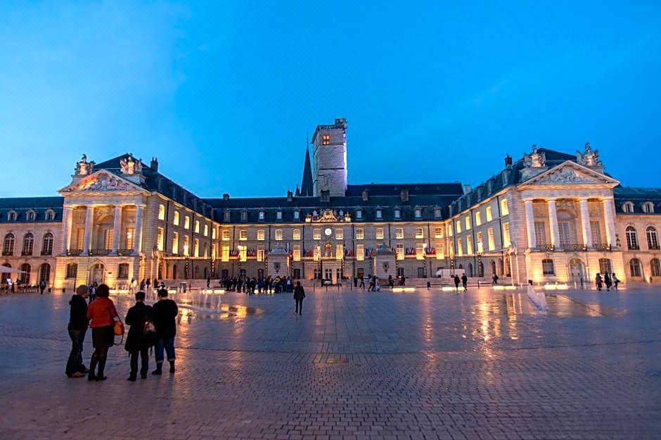 a large , well - lit building with people walking around in front of it at dusk at Novotel Dijon Sud