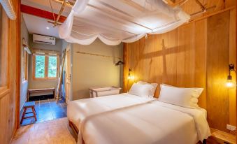 a large bed with white linens and a canopy is situated in a room with wooden walls at Topas Riverside Lodge