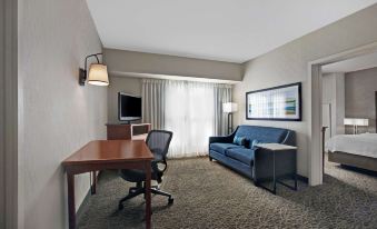 a hotel room with a couch , chair , desk , and window , along with other furniture and decorations at Homewood Suites by Hilton Chicago-Lincolnshire